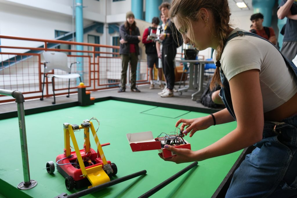 A female student works on the controls for a robot.