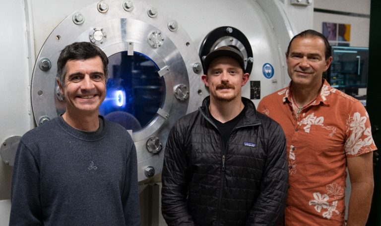 Professor Azer Yalin, Seth Thompson and Professor John Williams (L-R) in front of a thruster operating at CSU’s Center for Electric Propulsion and Plasma Engineering.