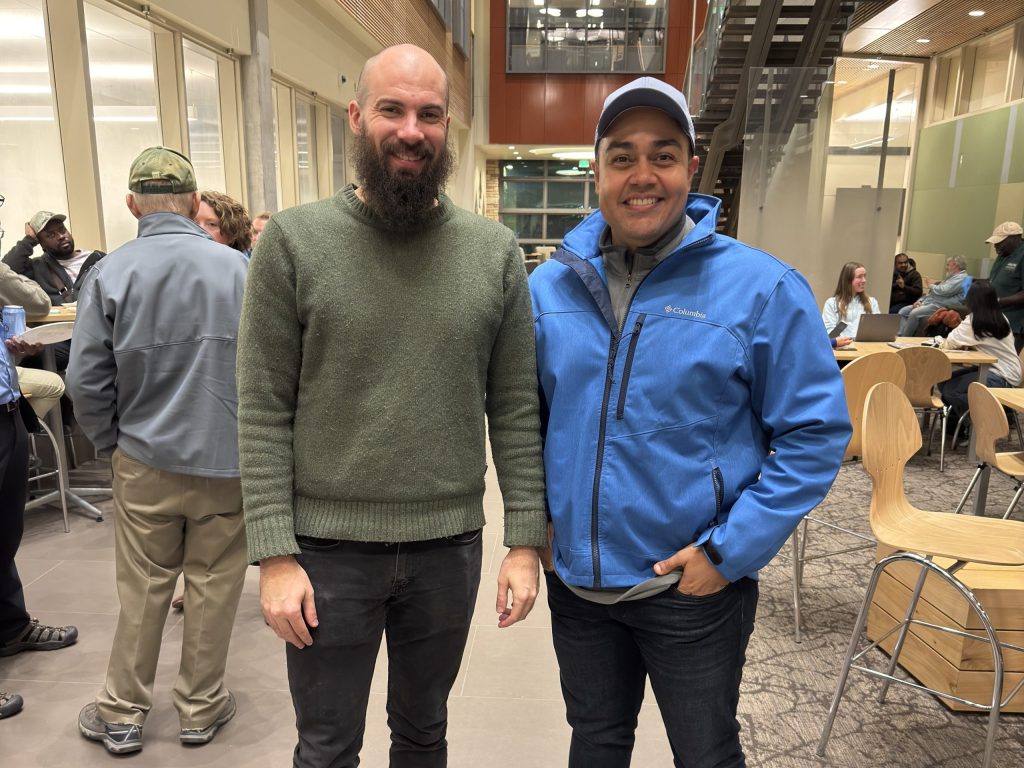 Two men pose for photo.