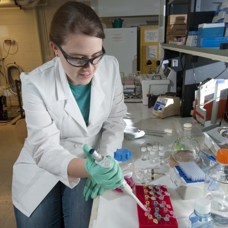 Female student in laboratory using pipette.