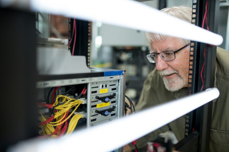 An older man is shown looking at the internal components of a computer.