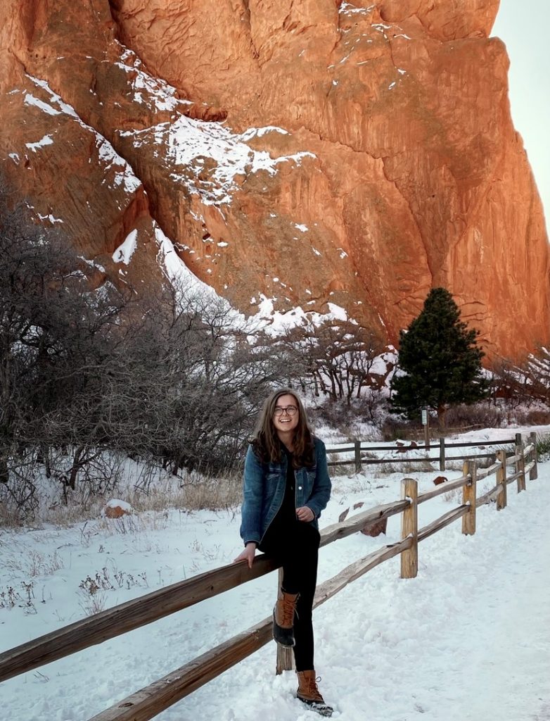 Sam White standing outside in front of a rock wall at Garden of the Gods. 
