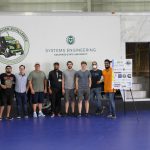 Group of students standing in front of a white truck with a green CSU Systems Engineering logo and CyberTruck challenge logo
