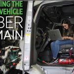 Person sitting inside of a heavy-duty truck typing into their laptop as part of the CyberTruck Challenge 2021