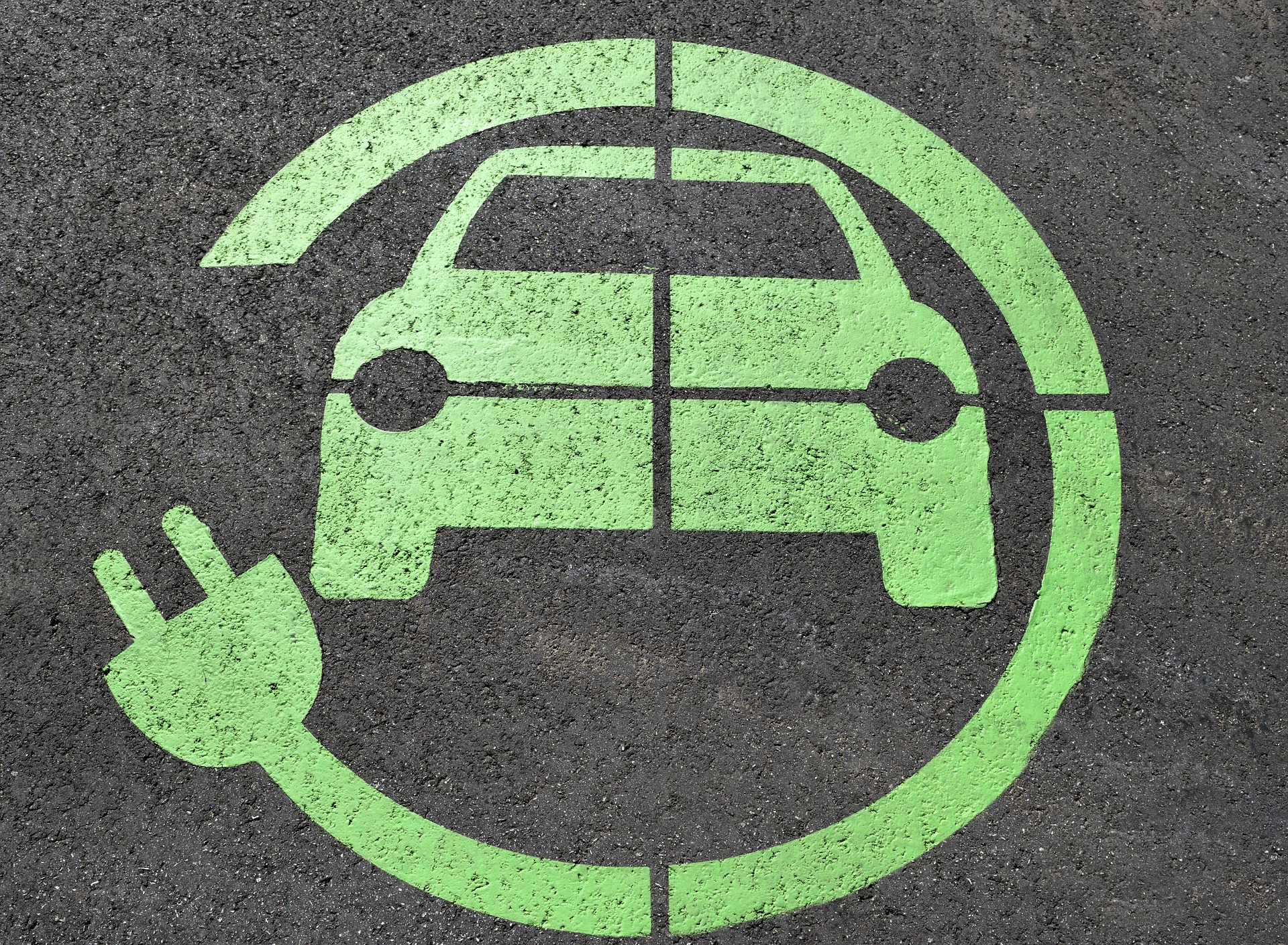 Green icon with a car and a plug wrapping around it printed on the ground. Indicates this is where an electric vehicle can be charged.
