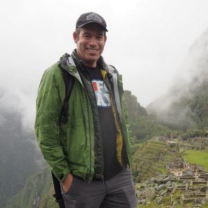 A man stands on a mountain top overlooking an ancient city.