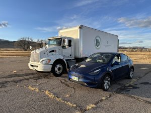 A CSU-branded commercial truck sits next to a Tesla car.