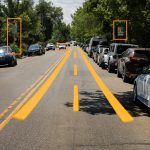 Image of a normal street with lane lines digitally painted over and boxes highlighting street signs.