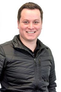Professional image of a smiling man in a light puff coat.