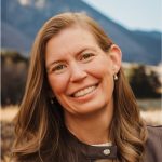 A woman outside with a mountain behind her.