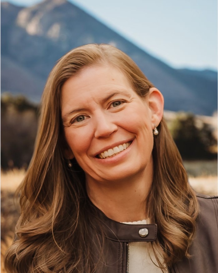 A woman outside with a mountain behind her.