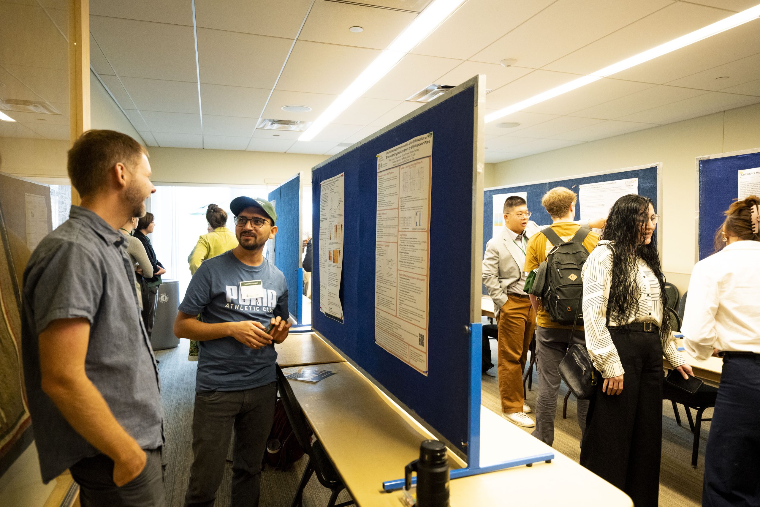 People fill a conference room to view research posters.
