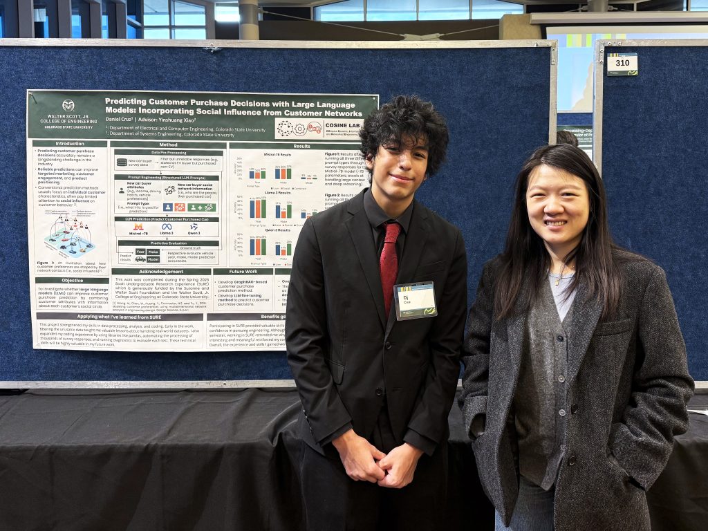 A young man stands with a woman in front of a Systems Engineering research poster.