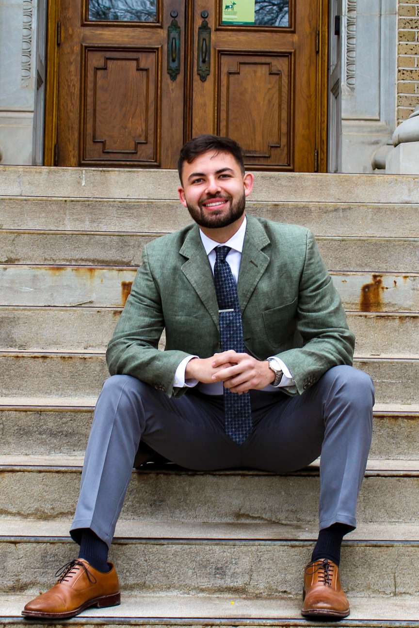 A man in a suit sits on concrete steps.