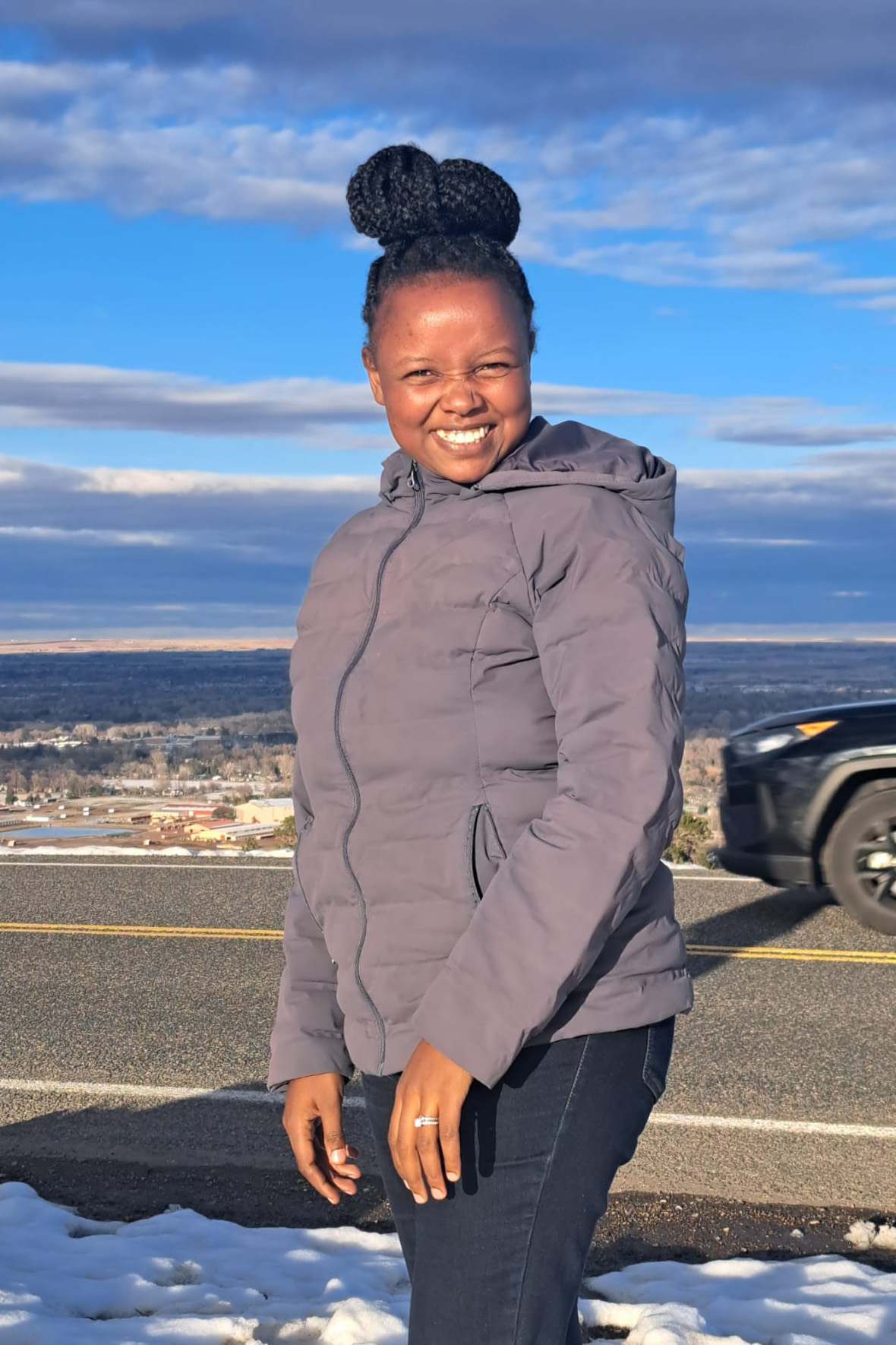 A woman in a puffer coat outside by a road.