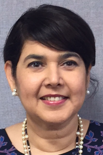 A woman with a short haircut, pearl necklace and pearl earrings.