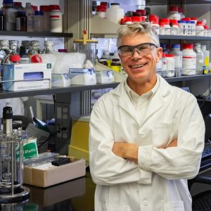 CBE Professor Ken Reardon stands in front of lab supplies and devices