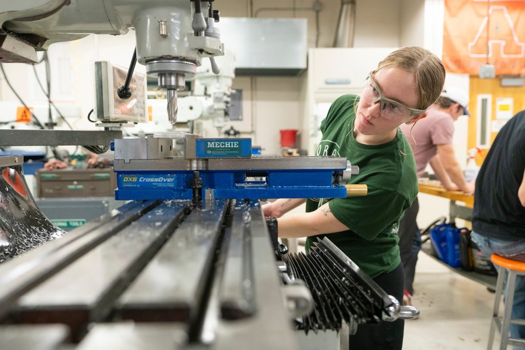 A mechanical engineering student works at a machine in a lab.