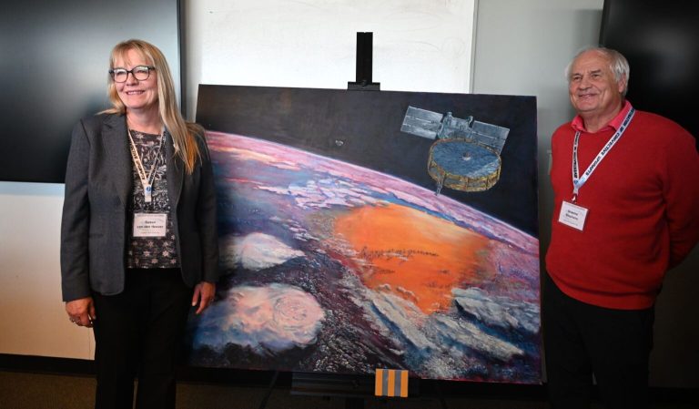 University Distinguished Professor Sue van den Heever, lead scientist on the INCUS mission, celebrates a painting donated to the Department of Atmospheric Science by emeritus University Distinguished Professor Graeme Stephens.