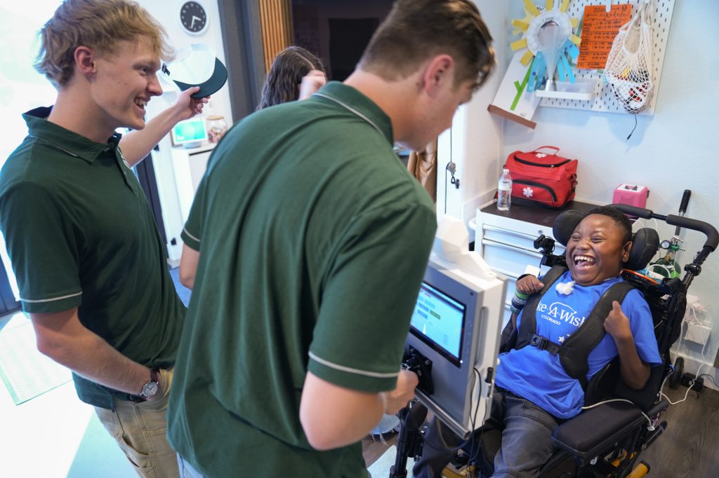 CSU Engineering students work with Lamar, a 13-year-old boy from Denver, to connect a device.