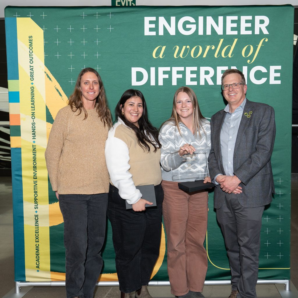 Erin Meier, Claudia Hernandez, Kayla Cothrun, and Allen Robinson pose in front of an Engineer a World of Difference backdrop at the 2026 All-college spring meeting.